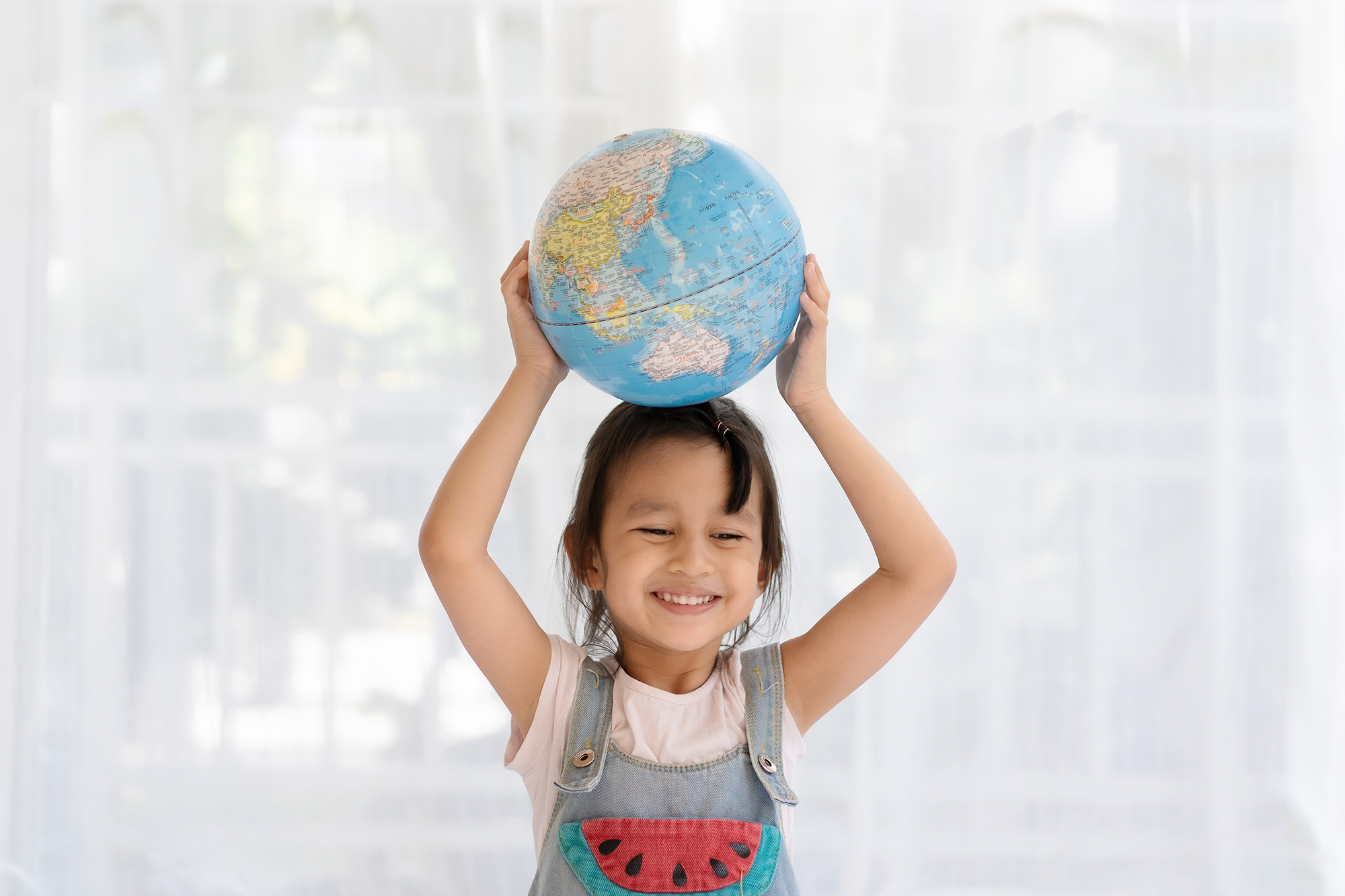 small girl holding a globe above her head